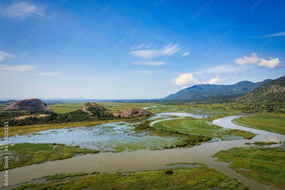 Beautiful shot of the Waku-Kungo landscape in Angola, featuring rolling hills and a stream Beautiful shot of the Waku-Kungo landscape in Angola, featuring rolling hills and a stream
