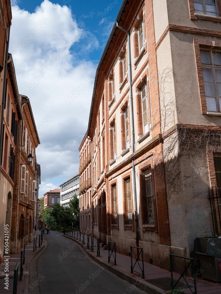 Obraz premium Narrow street lined with red brick buildings in Toulouse