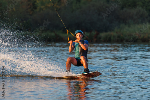 An athlete performs a trick on the water. Park at sunset. Wakeboard rider