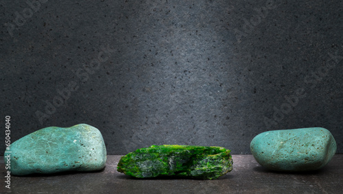 green chrome diopside stone on a dark gray background for a product presentation podium. natural green stones on a gray background for the presentation of perfumes, jewelry, cosmetics, medicines. photo