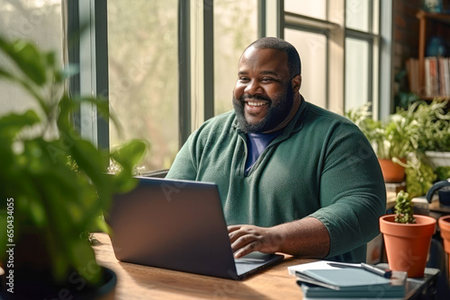 Portrait of an overweight African American man working from home on a laptop computer