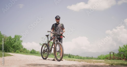 Male mountain biker fully geared portrait. Exploring dirt road in a scenic meadow. Adventure in a picturesque landscape. photo