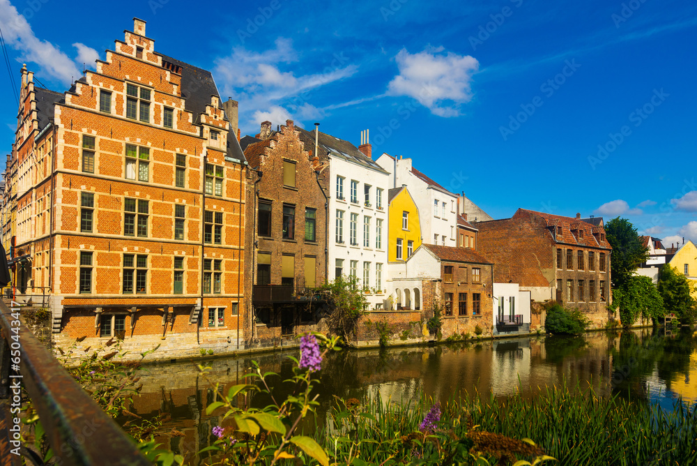 Picturesque summer view of Ghent with typical Flemish style townhouses located on banks of river Leie flowing through city center, Belgium..
