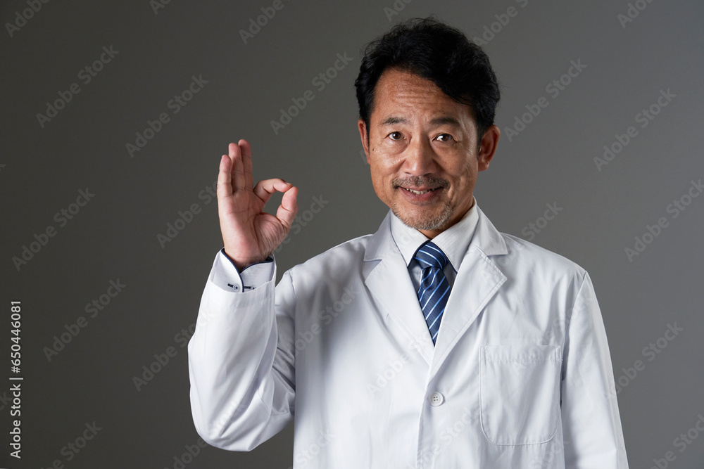 OKポーズをする中年の医師　黒背景