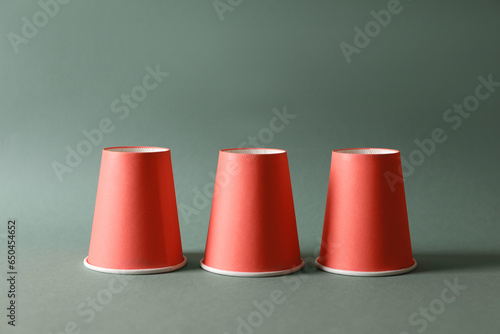 Photos Three red cups on pale olive background. Thimblerig game