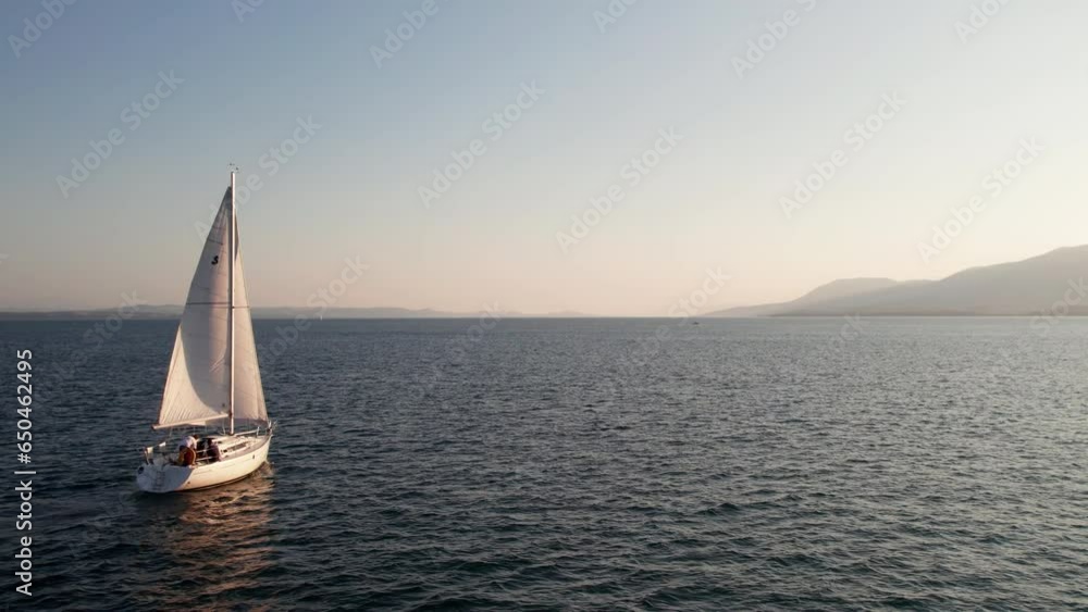 Back View of Sailing Yacht with a Young Crew Cruising on the Lake Neuchâtel, Switzerland, In the Background is the Romatic City of Neuchâtel, Beautiful Sunset over the Jura Hills, 50 FPS, Slomo Back View of Sailing Yacht with a Young Crew Cruising on the Lake Neuchâtel, Switzerland, In the Background is the Romatic City of Neuchâtel, Beautiful Sunset over the Jura Hills, 50 FPS, Slomo