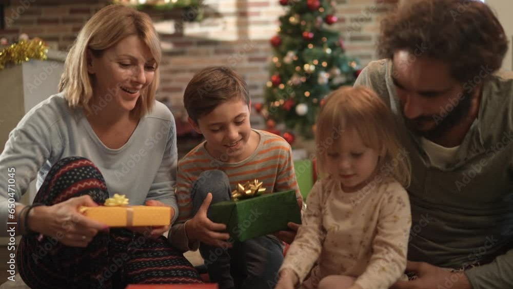 Happy young caucasian family opening presents on Christmas morning during the holiday season Happy young caucasian family opening presents on Christmas morning during the holiday season