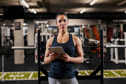Portrait of a female personal trainer holding tablet and looking at the camera.