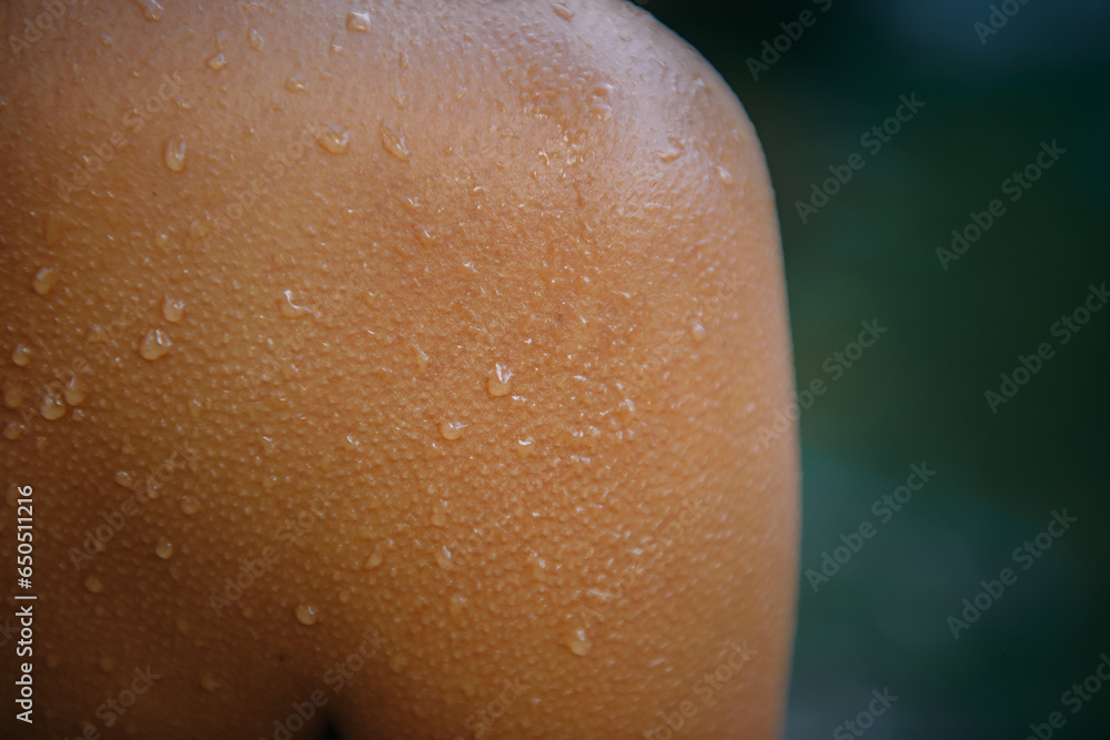 Fototapeta premium Close-up female tanned shoulder, showing skin detail with water droplets and goose bumps. Part of young sexy woman body. Blurred background, copy space.