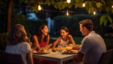 Portrait of a smiling family dining in the backyard of a house, happy young family eating lunch in garden