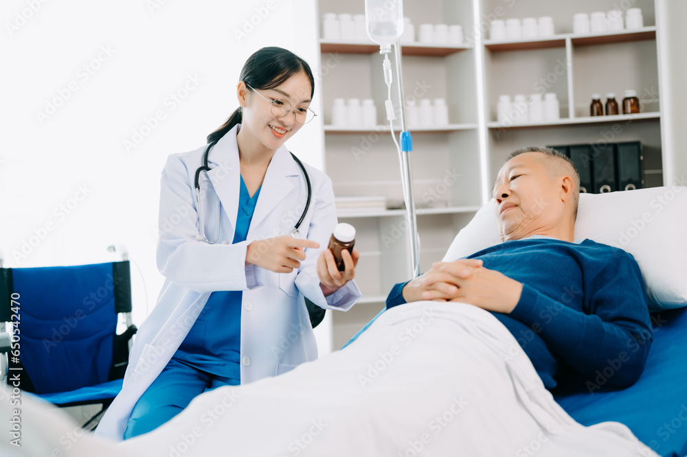 Asian doctor in white suit take notes while discussing and Asian elderly, man patient who lying on bed with receiving saline solution in hospital . Asian doctor in white suit take notes while discussing and Asian elderly, man patient who lying on bed with receiving saline solution in hospital .