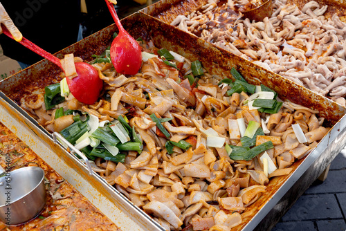 한국의 전통시장 거리에서 판매중인 돼지 껍데기 볶음 요리와 국자로 요리중인 상인의 손  photo