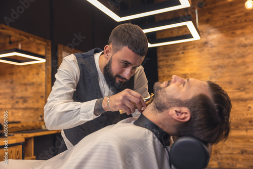 Caucasian man getting perfect shape of beard at barbershop.