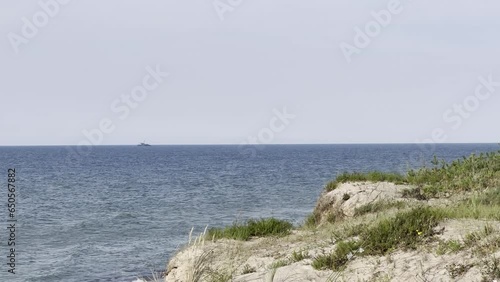A peaceful day in Latvia, Ventspils, Baltic Sea. Windy, sunny chill relaxation at the beach, with a view of the sea, ship, and dune.