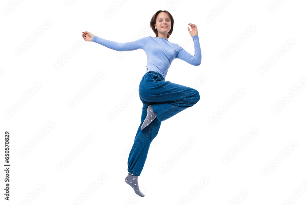 Portrait of teen smiling girl in casual blue clothes jumping against white background