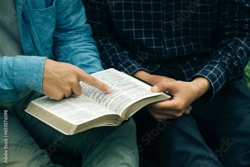 Two men read and studied the bible at the park and prayed together. sharing the gospel with a friend. Holy Bible study reading together on Sunday.Studying the Word Of God With Friends. Education. photo