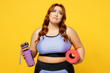 Young sad exhausted chubby overweight plus size big fat fit woman wear blue top warm up train hold yoga mat bottle of water isolated on plain yellow background studio home gym. Workout sport concept.