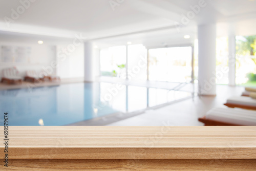 Brown wooden tabletop and blurred summer resort indoor swimming pool