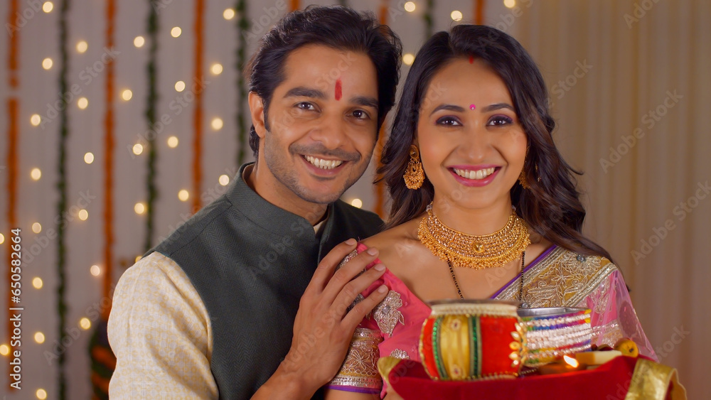 Indian husband-wife posing and smiling while looking into the camera - celebrating Karwa Chauth