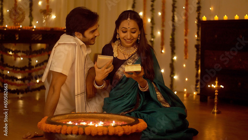 Indian man giving a Diwali present to his wife  at home - Celebrating Diwali. Loving husband gives a surprise gift to her wife on the occasion of Diwali with a Hug - Celebration Concept photo