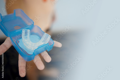 transparent mouth guard made of silicone, for straightening teeth in children, in a girl's hand, in daylight. Hygiene, dental care, occlusion correction, new technologies