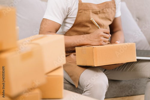 Shipping shopping online ,male start up small business owner writing address on cardboard box at workplace.small business entrepreneur SME or freelance man working with box at home.