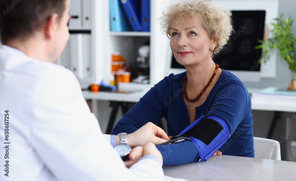 Doctor measures blood pressure of an elderly woman in medical office. Blood pressure in the elderly concept Doctor measures blood pressure of an elderly woman in medical office. Blood pressure in the elderly concept