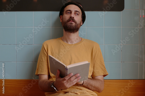 Handsome young man in a yellow T-shirt with a book in his hands