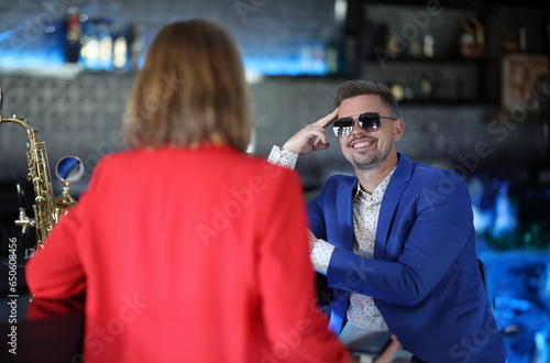 Canvas Print Smiling confident man in sunglasses meets woman near bar counter