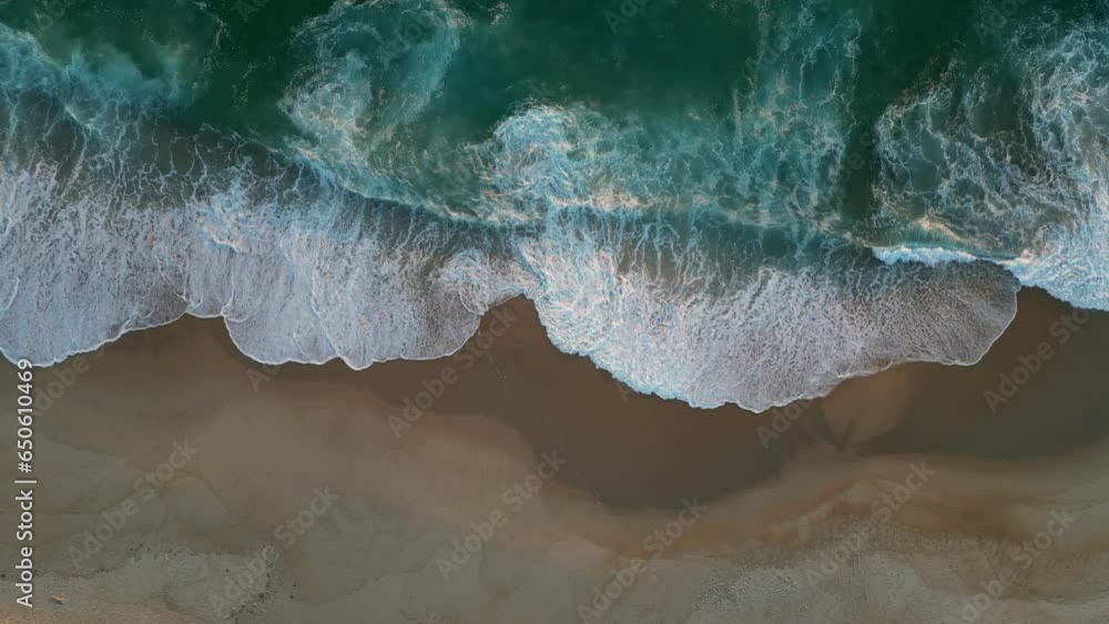 Waves with white foam on sandy shore at sunset. Aerial top down view of ...