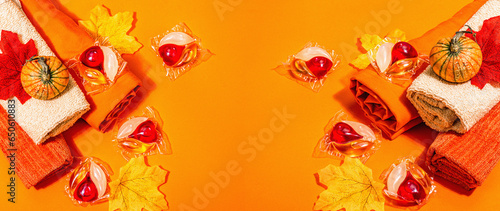 Machine washing concept. Capsules with detergent, soft towels and autumn decor. Laundry pods