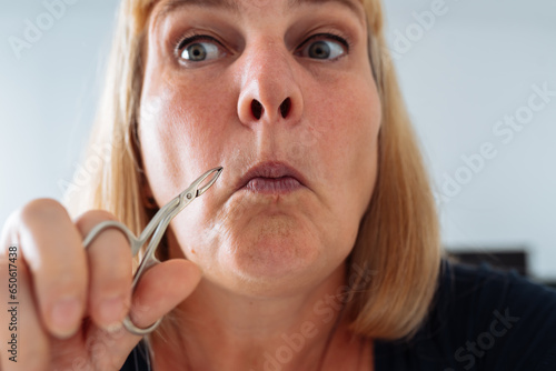 portrait woman plucking facial hair with tweezers