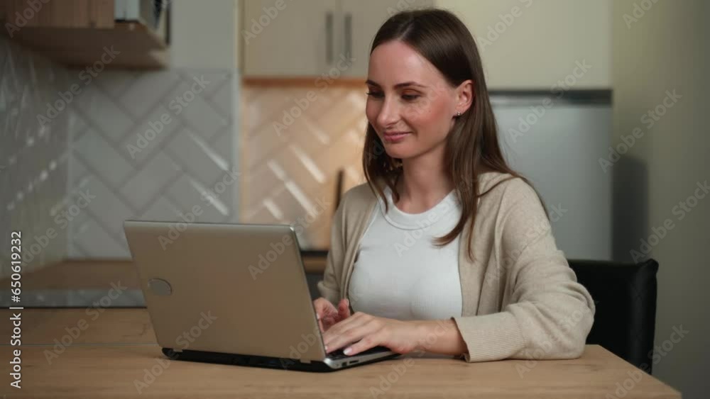 Young woman working online in her kitchen with a laptop. Young woman working online in her kitchen with a laptop.