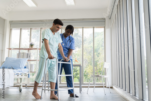 Obraz na plátne Young female nurse help patient man walk with walker careful at hospital
