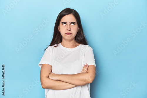 Young Caucasian woman on blue backdrop tired of a repetitive task.