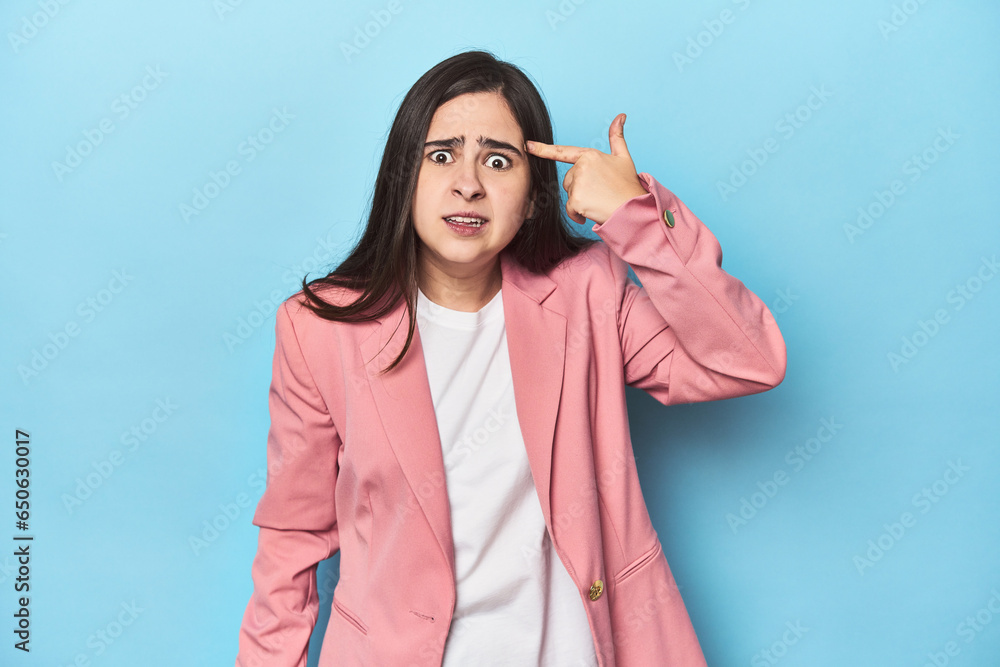Young Caucasian woman on blue backdrop showing a disappointment gesture with forefinger. Young Caucasian woman on blue backdrop showing a disappointment gesture with forefinger.