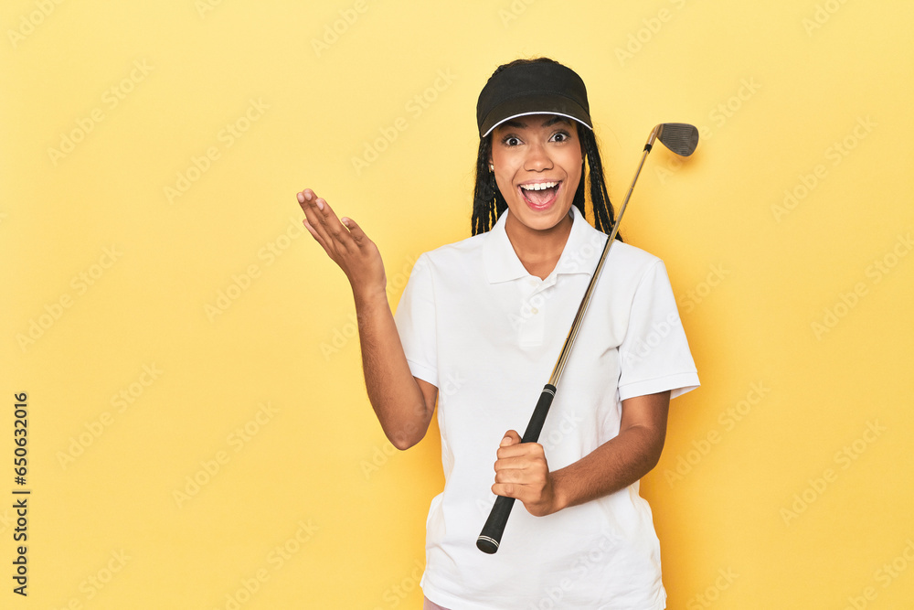 Indonesian female golfer on yellow backdrop receiving a pleasant surprise, excited and raising hands. Indonesian female golfer on yellow backdrop receiving a pleasant surprise, excited and raising hands.
