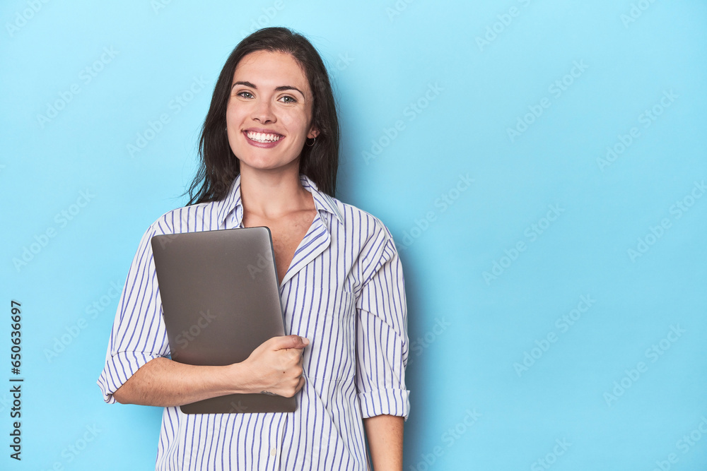 Young businesswoman holding laptop on blue happy, smiling and cheerful. Young businesswoman holding laptop on blue happy, smiling and cheerful.