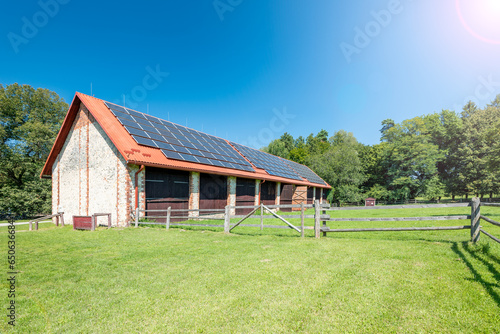 Big brick barn on a farm. Solar panels installed on the roof of the barn.