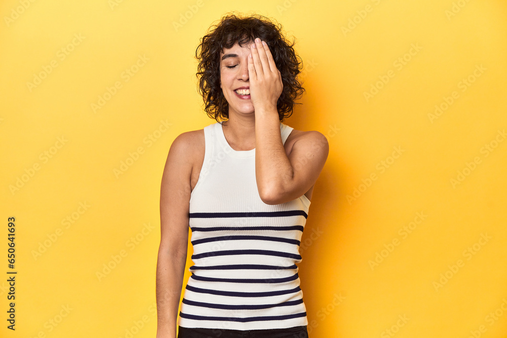 Caucasian curly-haired woman in white tank-top having fun covering half of face with palm. Caucasian curly-haired woman in white tank-top having fun covering half of face with palm.