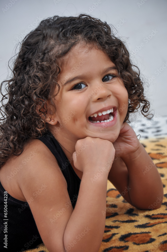 child posing in studio with white background. curly girl smiling at camera in black clothes child posing in studio with white background. curly girl smiling at camera in black clothes
