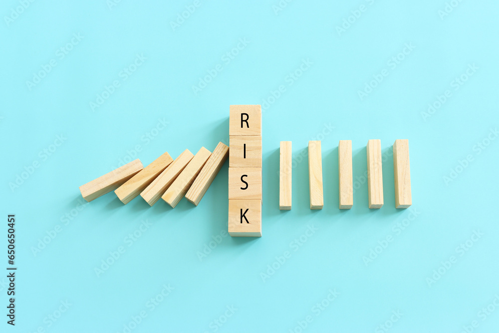 Wooden cubes with the text risk, stopping the domino effect. success and challenge concept Wooden cubes with the text risk, stopping the domino effect. success and challenge concept