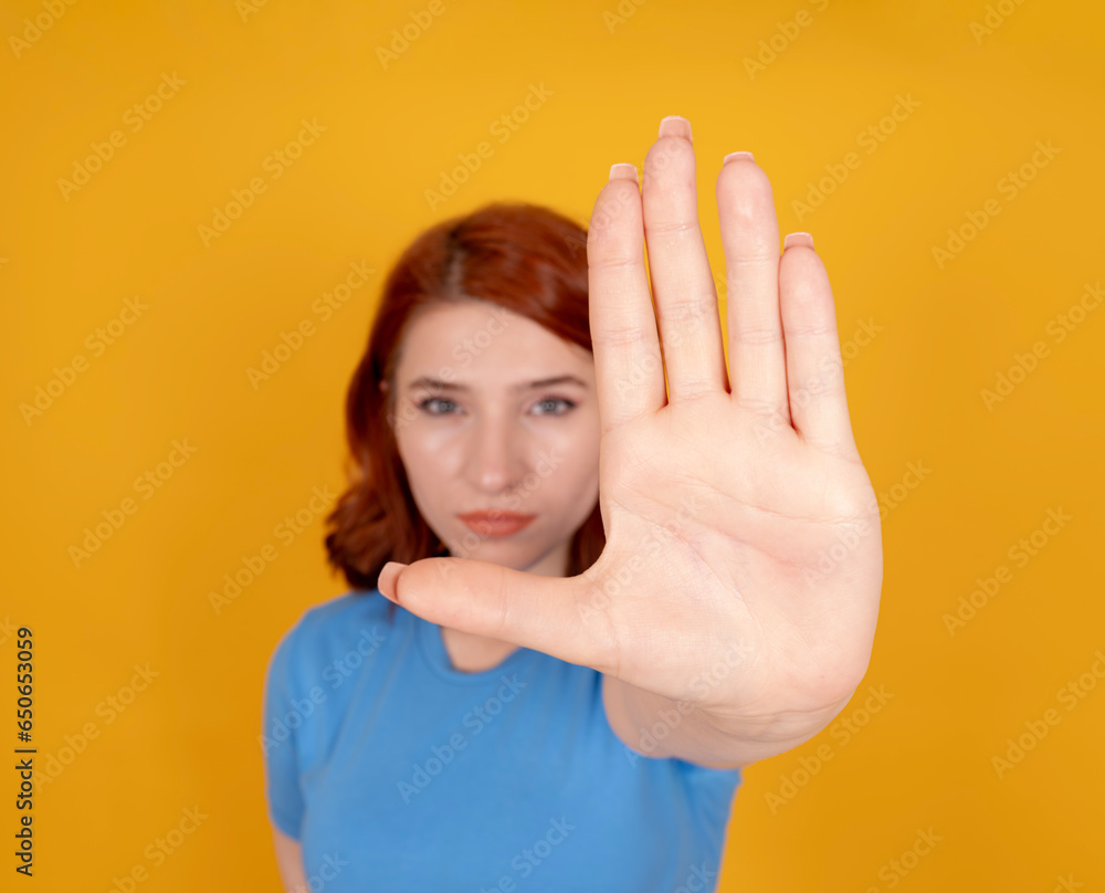Showing stop gesture with palm, close up image of caucasian red bob hair woman showing stop gesture with palm. Selective focus on hand, blurred face. Displeased, dissatisfied girl in 20s. Refuse. Showing stop gesture with palm, close up image of caucasian red bob hair woman showing stop gesture with palm. Selective focus on hand, blurred face. Displeased, dissatisfied girl in 20s. Refuse.