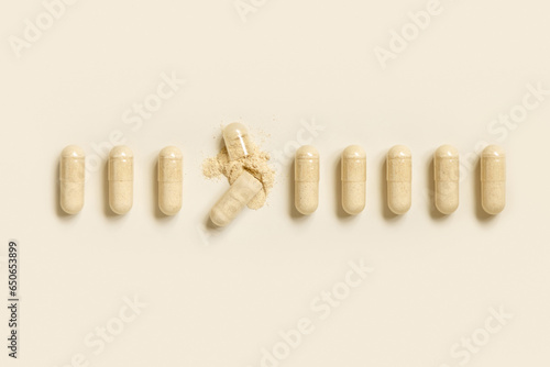 Medical capsules in a line with one opened to show beige powder top view. Dietary supplements photo