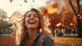 joyful woman having fun throwing leaves in autumn