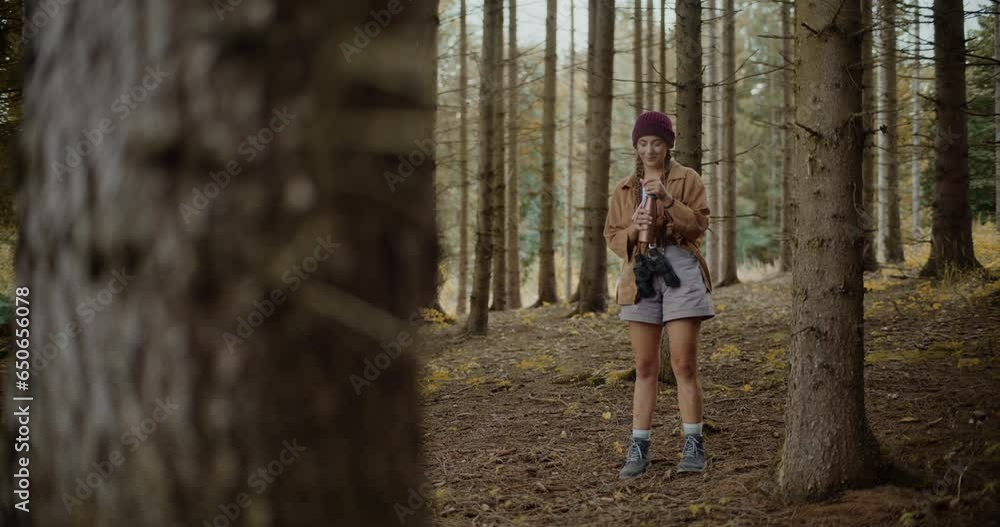 Woman opening bottle lid while exploring in forest Woman opening bottle lid while exploring in forest