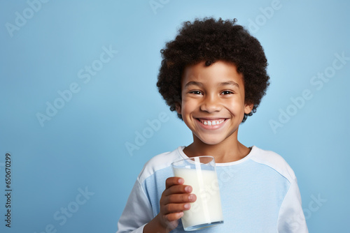 African American little boy happily drinking milk isolated on blue background photo