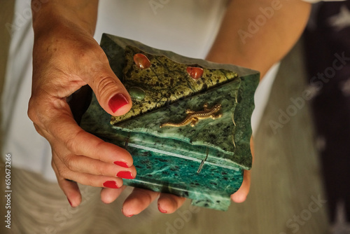 A beautiful young woman holds in her hands a malachite box with precious jewelry stones inside