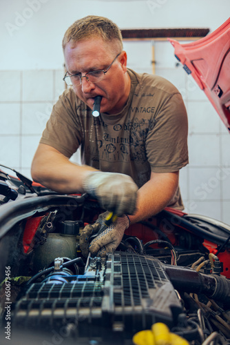 A Man with glasses Maintains a Car in a Garage