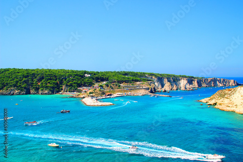 Impressive scenery from Tremiti Islands (Isole Tremiti) with the dulcet azure, emerald and blue hues of the Adriatic Sea crossed by many motorboats leaving white foamy wakes, a dock and rocky islands photo